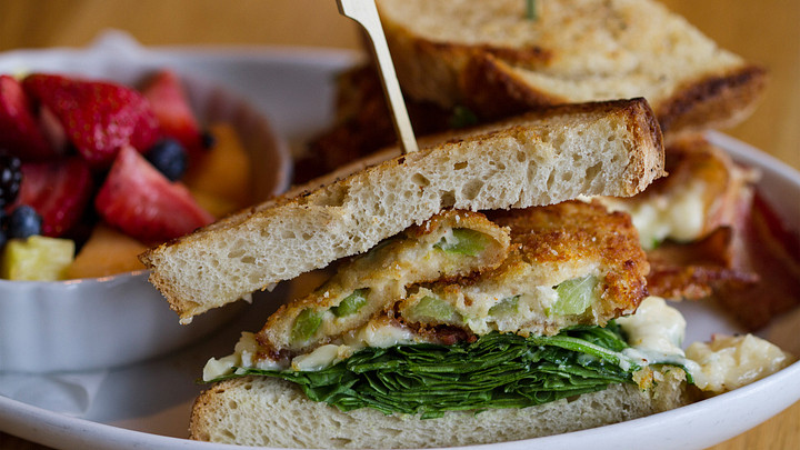 Fried green tomato sandwich with bowl of fruit