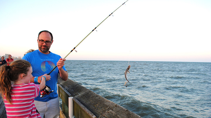 father and daughter fishing off a pier