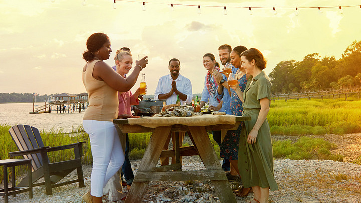 Group of people around table eating oysters and drinking wine on the water