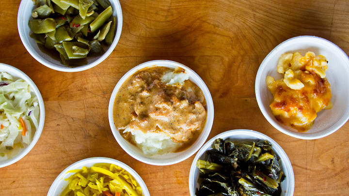 Bowls of green beans, collards, macaroni and cheese, slaw, mashed potatoes and gravy