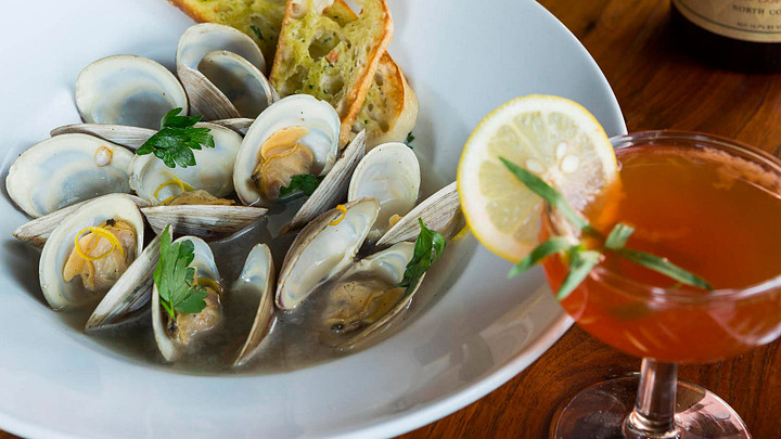 Dish of clams in broth with a cocktail 