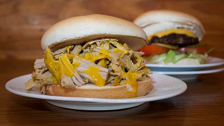 Plates of pulled pork barbecue sandwich with mustard sauce and cheeseburger 